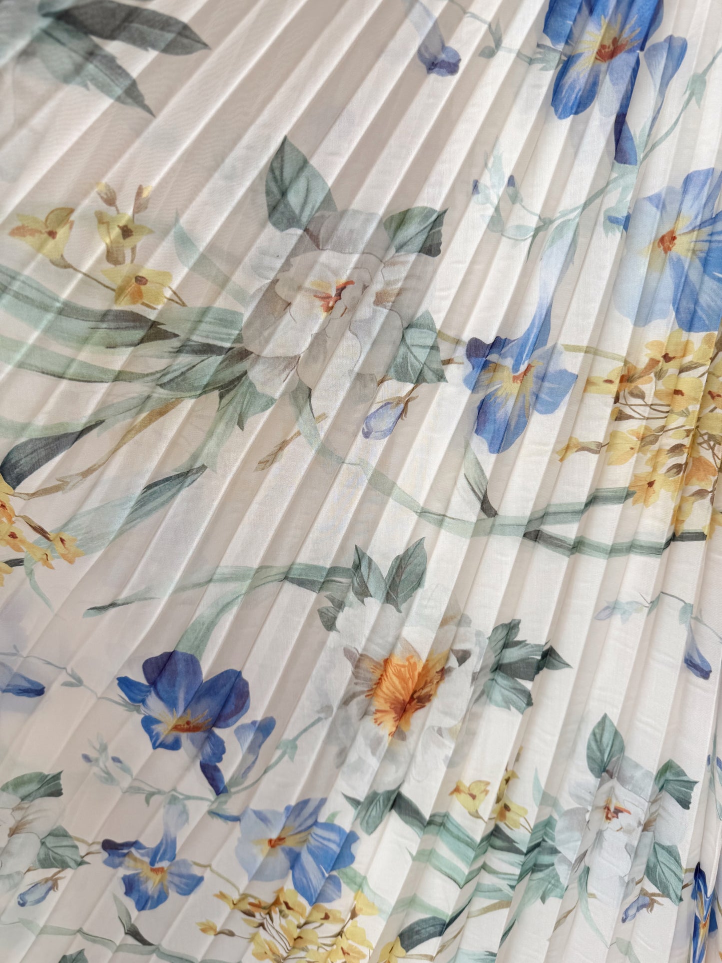 Floral patterned fabric with blue, yellow, and green flowers on a pleated background- Flowy fabric